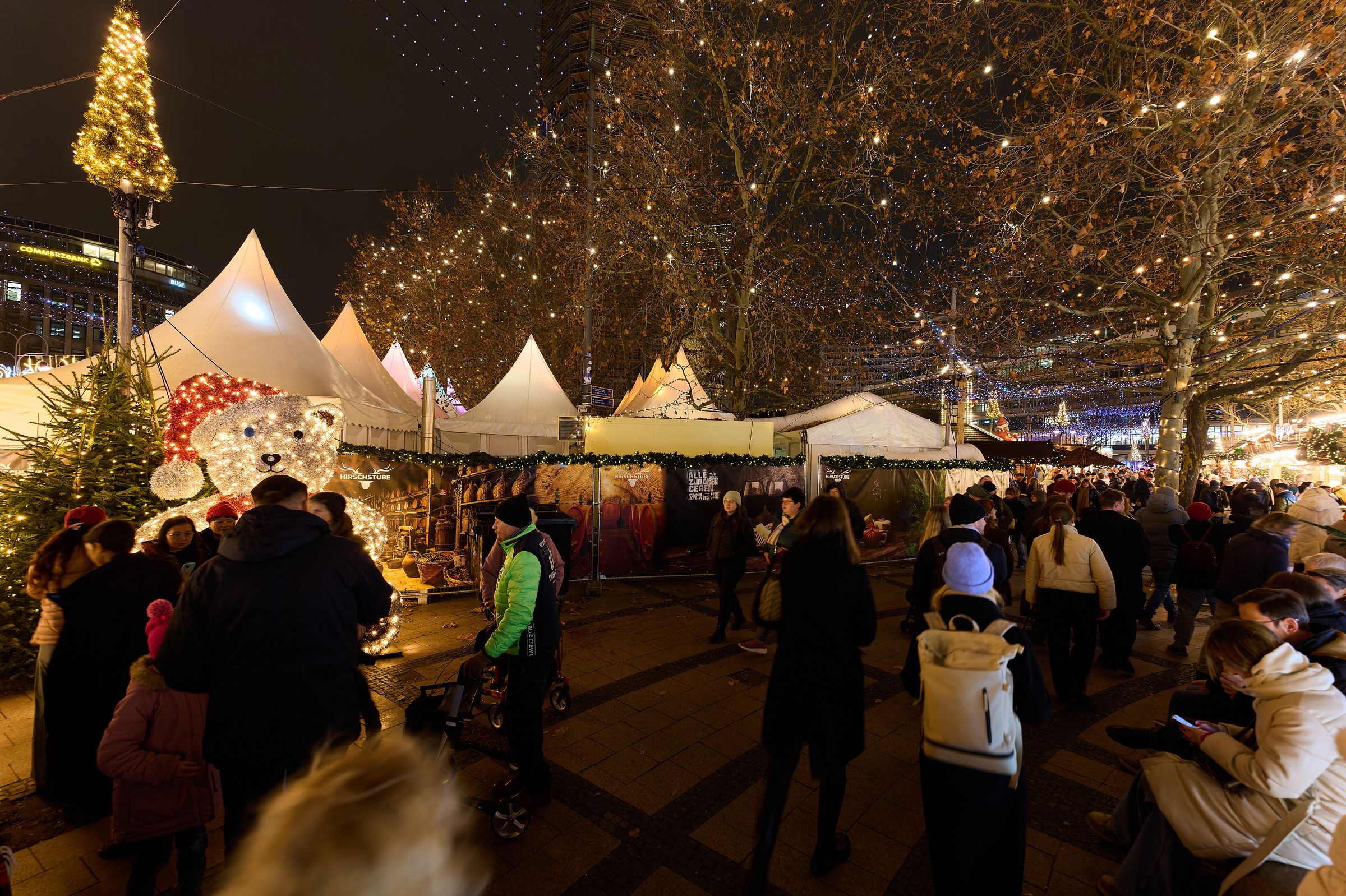Strings of lights over a busy Christmas market at night
